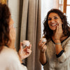 Mujer feliz y con el rostro radiante después de aplicarse la crema de noche antes de ir a dormir.